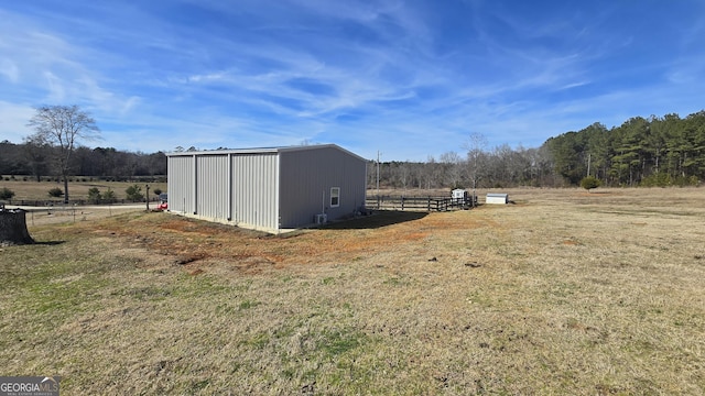 view of outdoor structure with a rural view, fence, and an outdoor structure