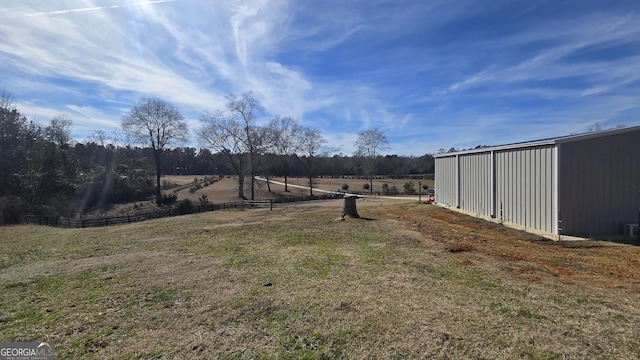 view of yard featuring an outbuilding, a rural view, an outdoor structure, and fence