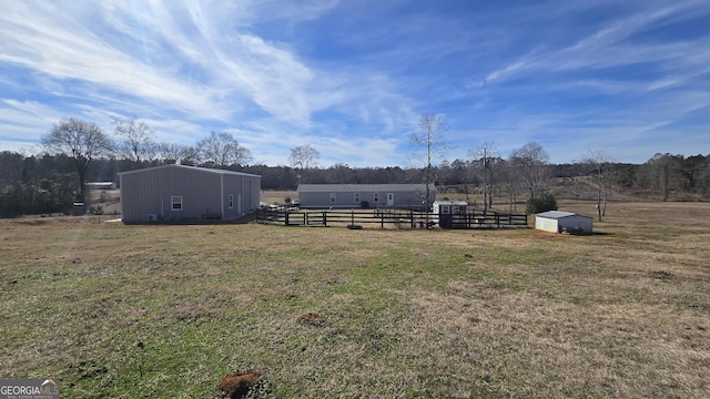 view of yard featuring an outbuilding, a rural view, fence, and an outdoor structure