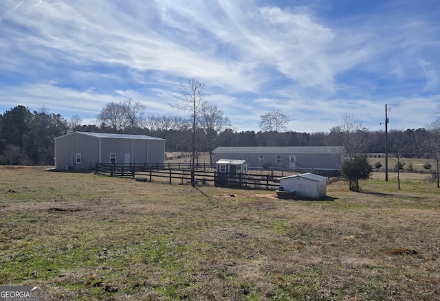 view of yard with an outbuilding, a rural view, an outdoor structure, and fence