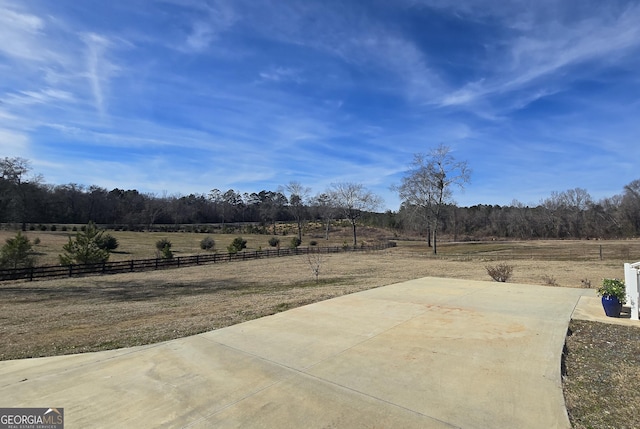 view of patio with fence and a rural view