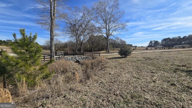 view of yard with fence and a rural view