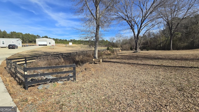 view of yard with an outbuilding, fence, driveway, and a detached garage