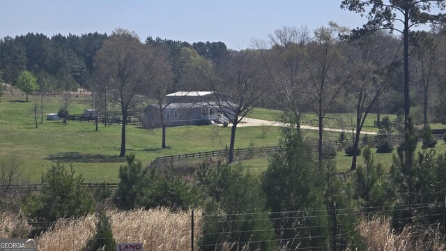 manufactured / mobile home featuring a fenced front yard, a detached garage, concrete driveway, a wooded view, and an outdoor structure