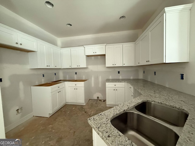 150 Asa Moseley Rd, Mcdonough, GA 30252 - kitchen with a sink, light stone counters, baseboards, unfinished concrete flooring, and white cabinets