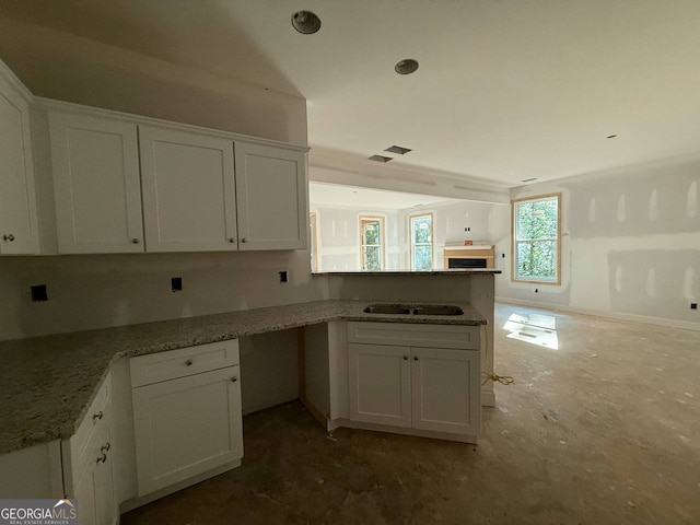 150 Asa Moseley Rd, Mcdonough, GA 30252 - kitchen with a peninsula, white cabinets, light stone counters, open floor plan, and a sink