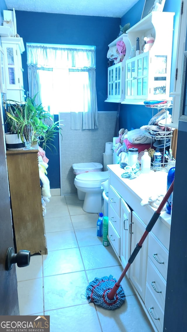 bathroom featuring tile walls, vanity, tile patterned flooring, and toilet