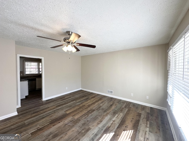 empty room featuring ceiling fan, dark wood-type flooring, and a textured ceiling