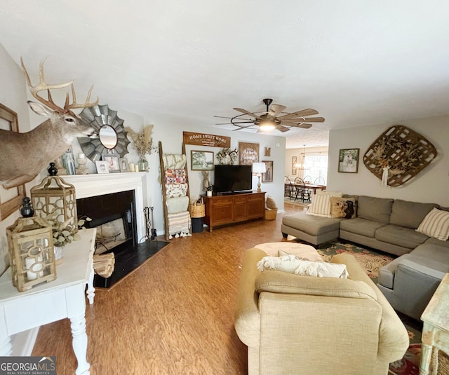 living room with ceiling fan, wood-type flooring, and a tiled fireplace