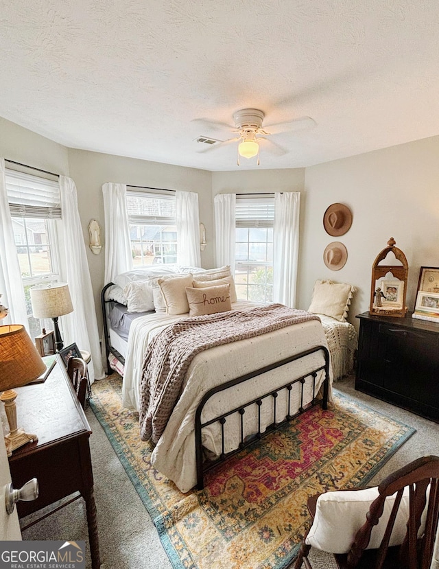 carpeted bedroom featuring a textured ceiling and ceiling fan