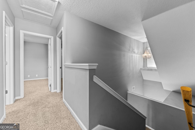 corridor featuring light carpet and a textured ceiling