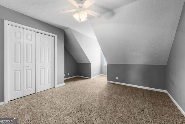 additional living space with ceiling fan, lofted ceiling, carpet flooring, and a textured ceiling