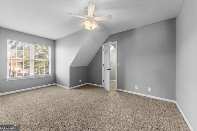 bonus room featuring ceiling fan, vaulted ceiling, carpet flooring, and a textured ceiling