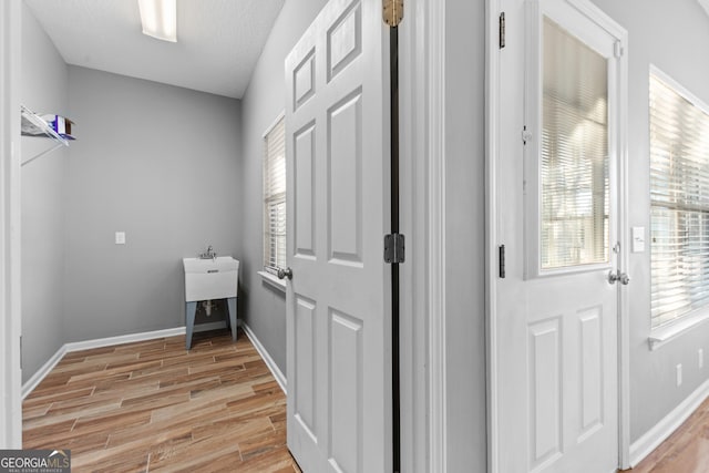 clothes washing area featuring a textured ceiling and light wood-type flooring