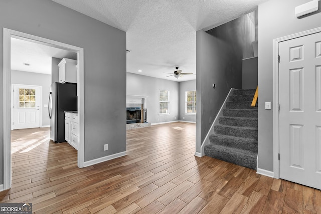 unfurnished living room with ceiling fan, a textured ceiling, and a fireplace