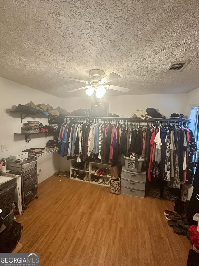 spacious closet with wood finished floors, visible vents, and a ceiling fan