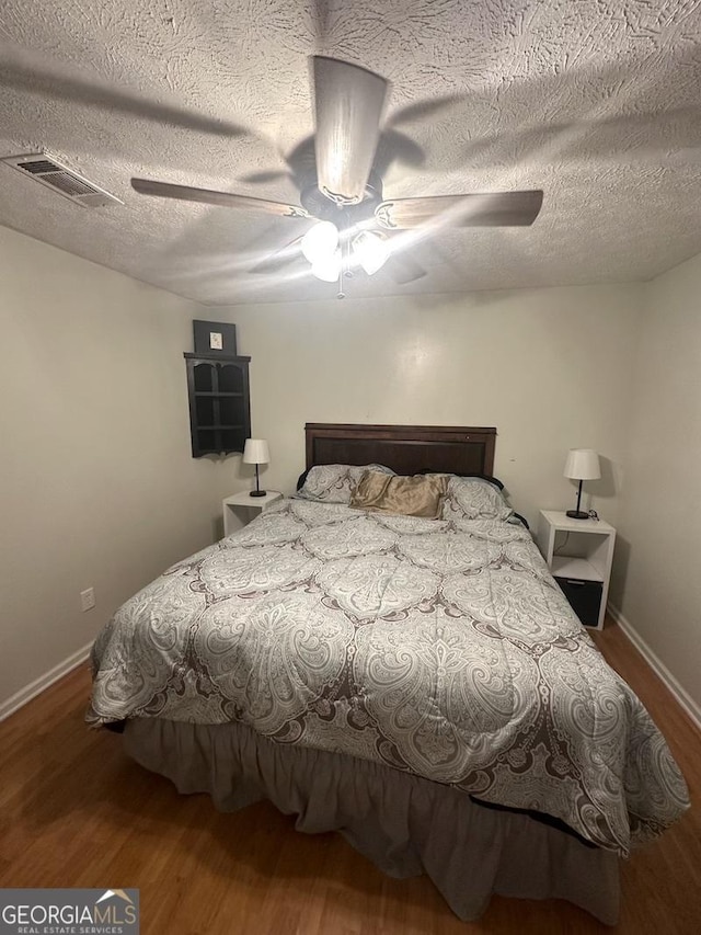 bedroom with visible vents, ceiling fan, a textured ceiling, and wood finished floors