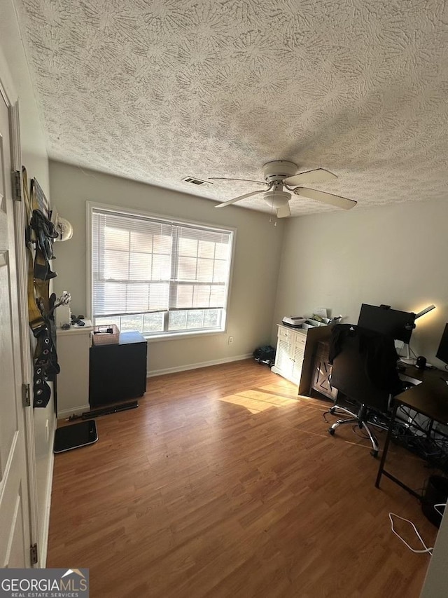 office featuring a ceiling fan, visible vents, a textured ceiling, and wood finished floors