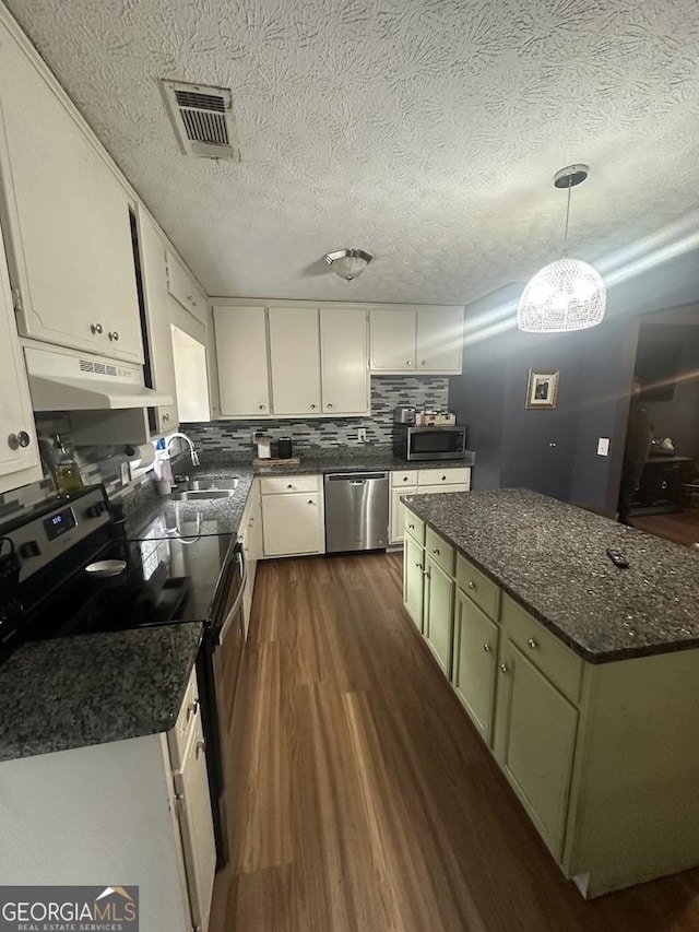 kitchen with under cabinet range hood, stainless steel appliances, a sink, visible vents, and dark wood-style floors