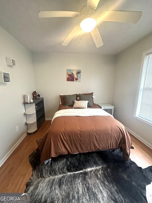 bedroom featuring a ceiling fan, baseboards, and wood finished floors