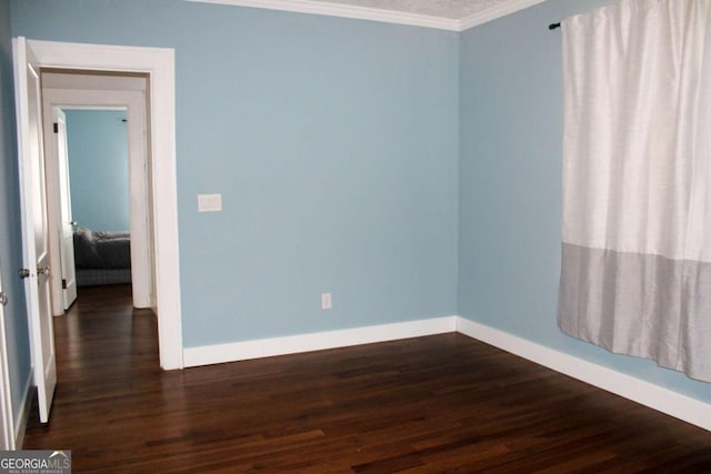 unfurnished room featuring dark wood-type flooring and ornamental molding