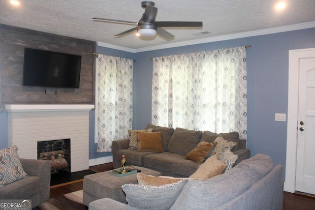 living room with ornamental molding, a brick fireplace, dark hardwood / wood-style floors, and a textured ceiling