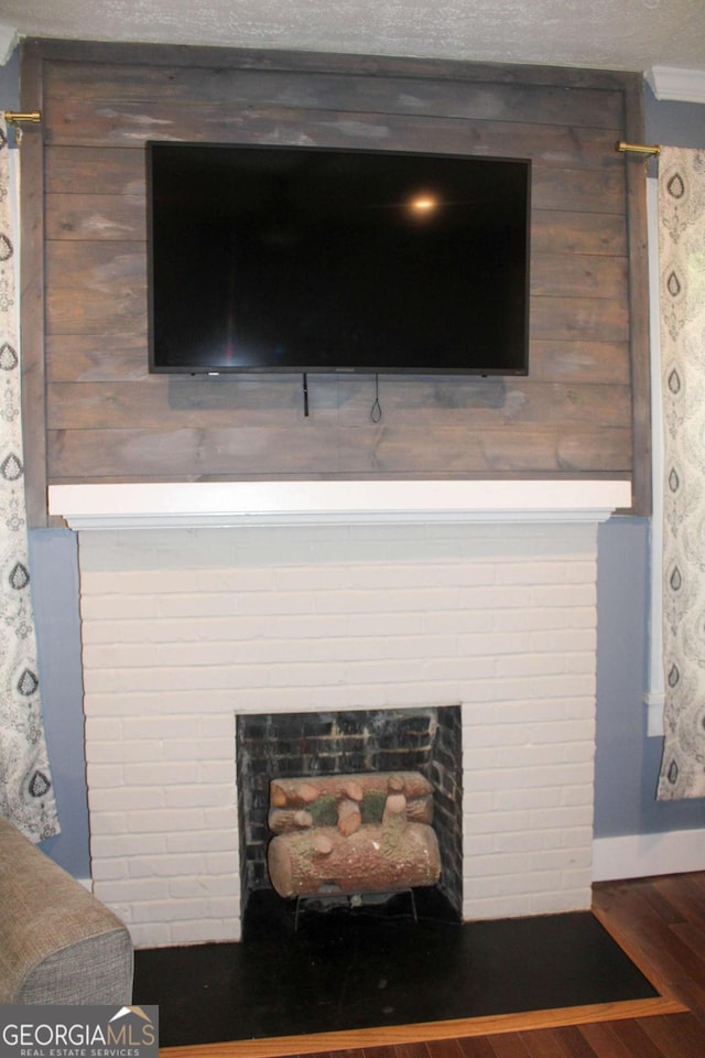 interior details with a brick fireplace, crown molding, and hardwood / wood-style floors