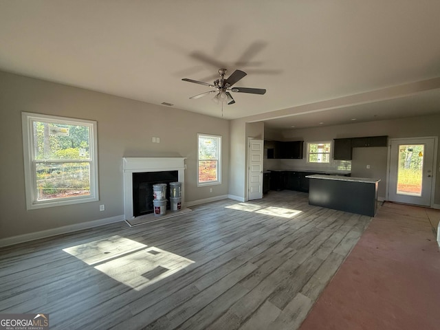 148 Asa Moseley Rd, Mcdonough, GA 30252 - unfurnished living room with light wood-type flooring, baseboards, a ceiling fan, and a fireplace with raised hearth