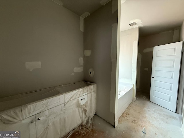 bathroom featuring a garden tub and concrete flooring