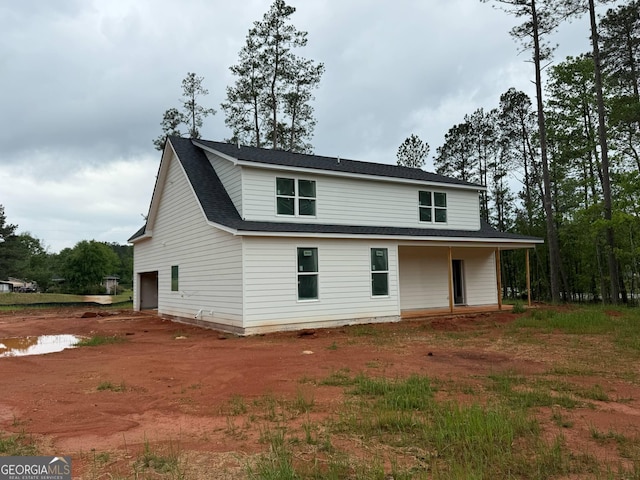 back of house with roof with shingles and dirt driveway