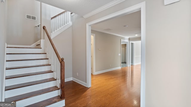 stairway featuring wood-type flooring and crown molding