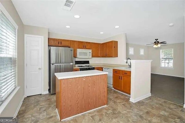 kitchen featuring sink, white appliances, ceiling fan, a center island, and kitchen peninsula