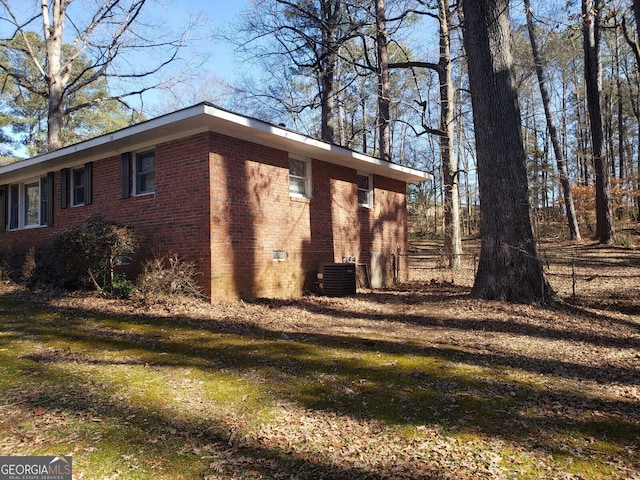 view of side of home with a yard and central AC