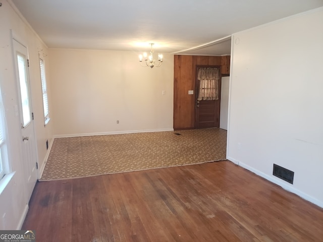 unfurnished room with a notable chandelier and dark wood-type flooring