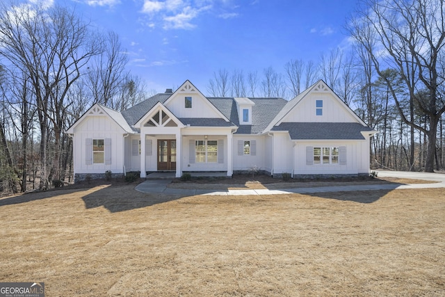 modern farmhouse style home featuring a shingled roof, a chimney, french doors, a front lawn, and board and batten siding