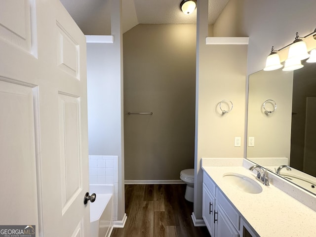 bathroom featuring a tub to relax in, hardwood / wood-style flooring, vanity, toilet, and a textured ceiling