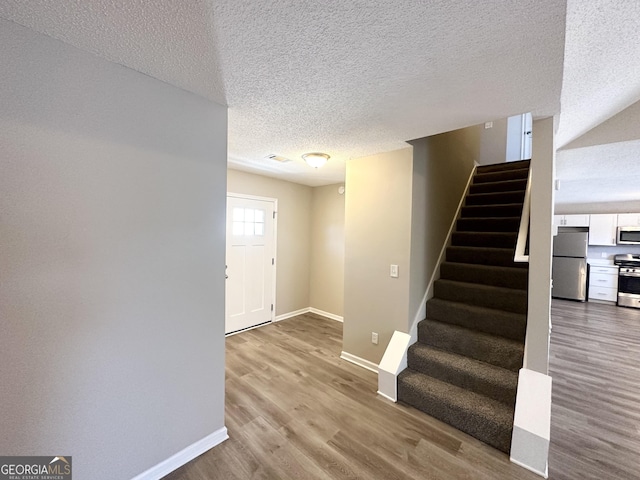 stairs featuring wood-type flooring and a textured ceiling