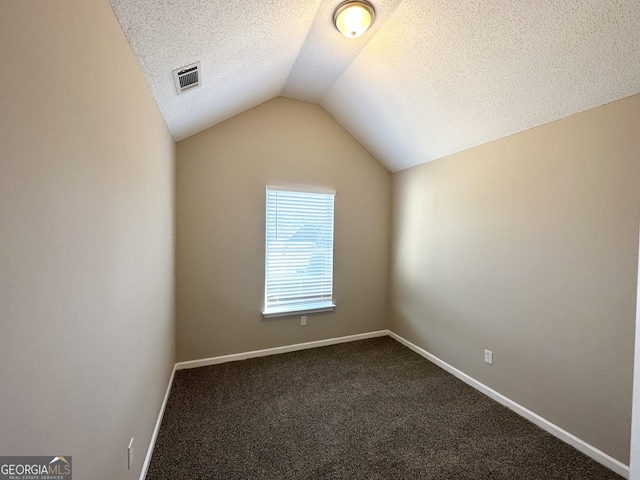 unfurnished room with lofted ceiling, carpet, and a textured ceiling