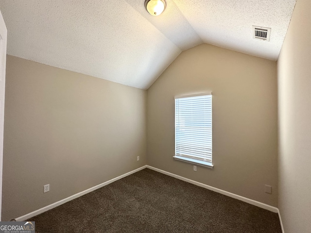 empty room featuring vaulted ceiling, carpet, and a textured ceiling