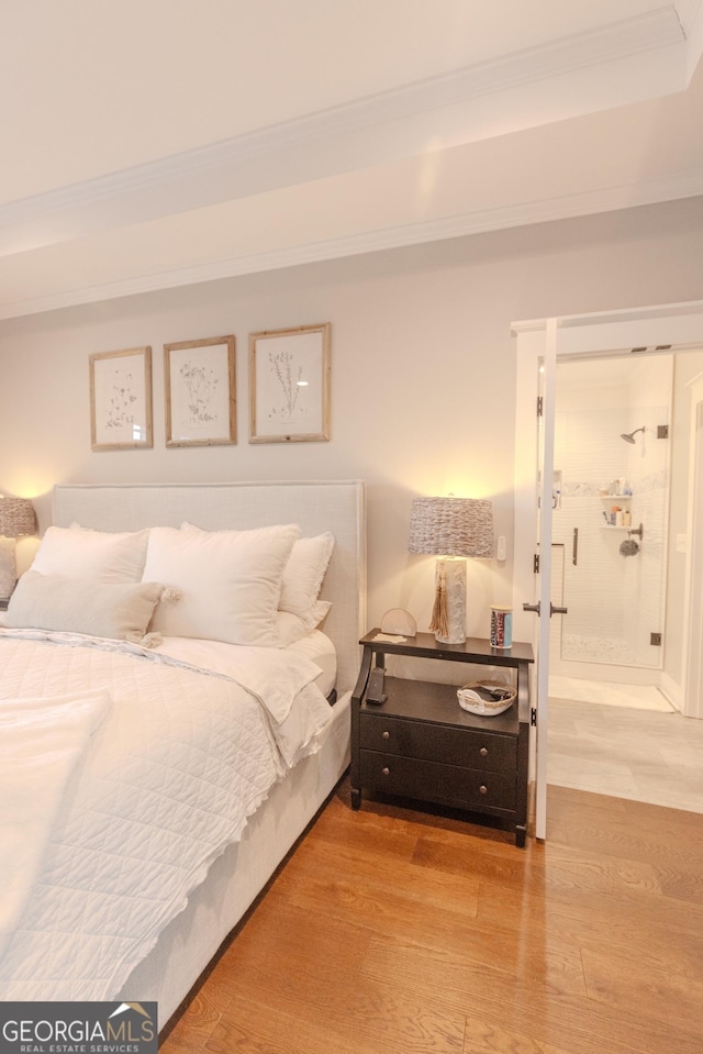 bedroom with hardwood / wood-style flooring, ornamental molding, and ensuite bath