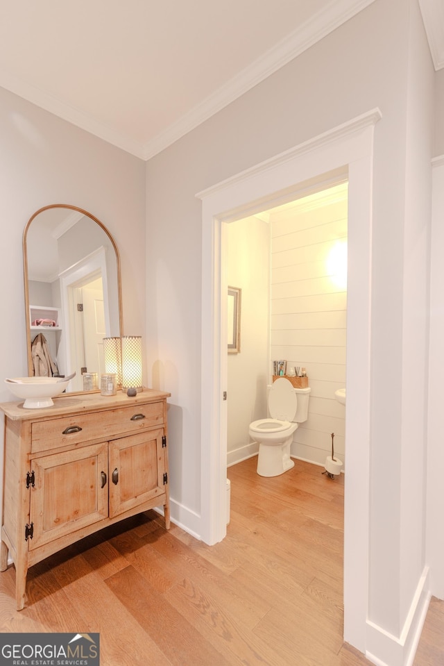 bathroom featuring hardwood / wood-style flooring, ornamental molding, toilet, and vanity