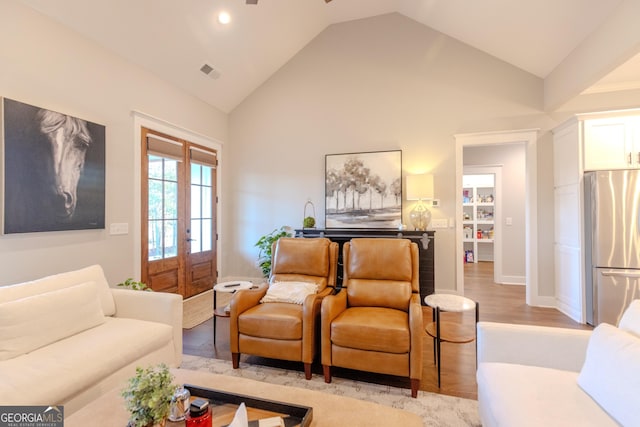 living room featuring french doors, lofted ceiling, and light hardwood / wood-style flooring