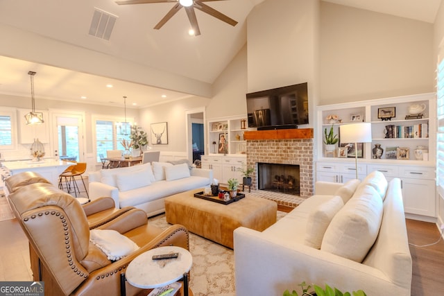 living room featuring a brick fireplace, light hardwood / wood-style flooring, high vaulted ceiling, and ceiling fan