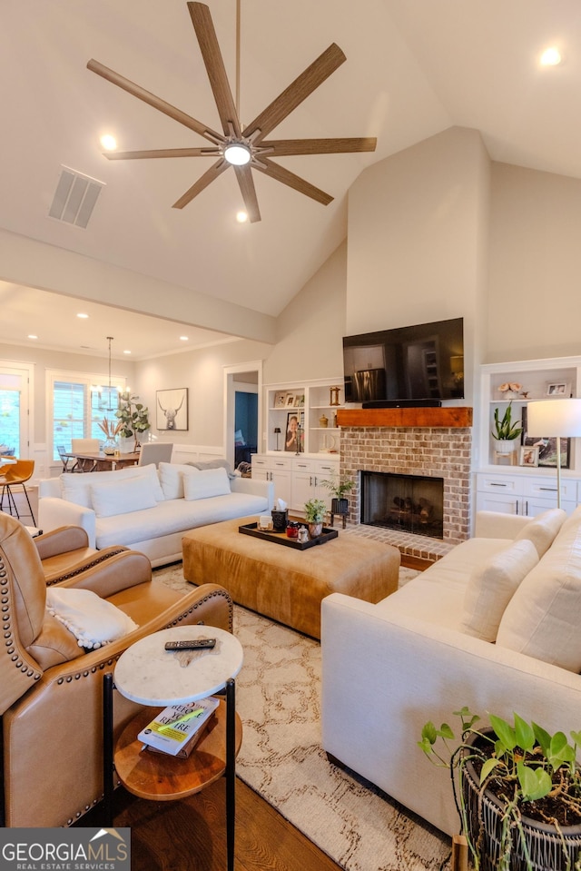 living room featuring lofted ceiling, a brick fireplace, built in features, hardwood / wood-style flooring, and ceiling fan