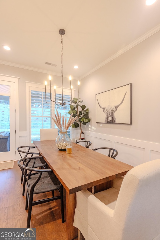 dining space featuring hardwood / wood-style flooring, ornamental molding, and a chandelier