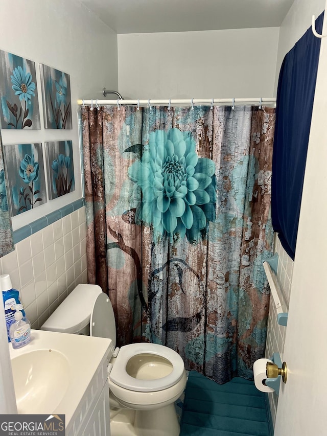 bathroom with a shower with curtain, vanity, tile walls, and toilet