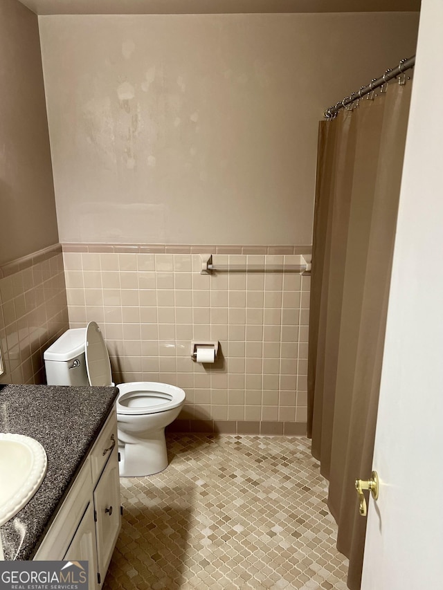 bathroom with vanity, tile walls, and toilet