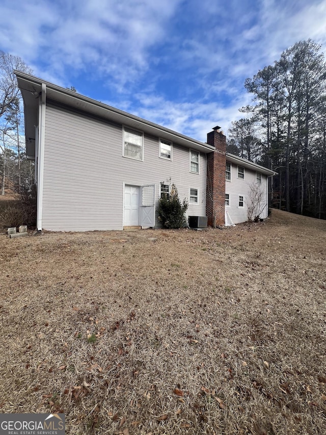 rear view of house featuring central AC and a yard