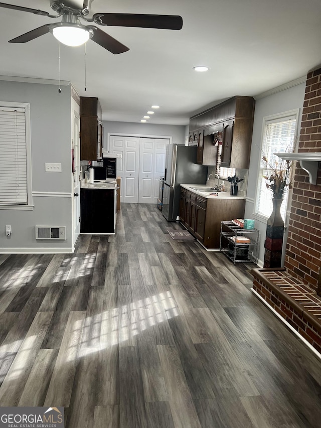 kitchen with dark hardwood / wood-style floors, sink, stainless steel fridge, ornamental molding, and dark brown cabinetry