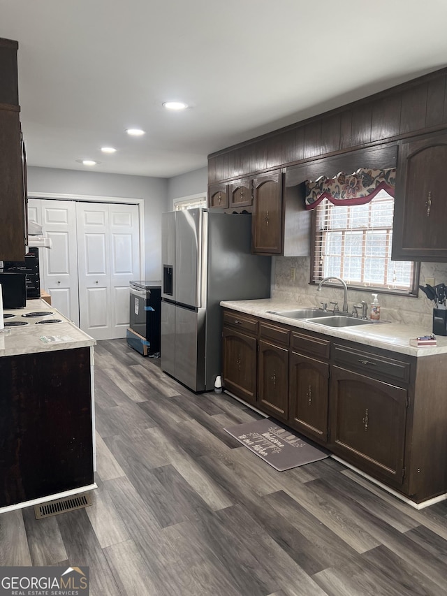 kitchen featuring dark wood-type flooring, stainless steel refrigerator with ice dispenser, sink, tasteful backsplash, and dark brown cabinets